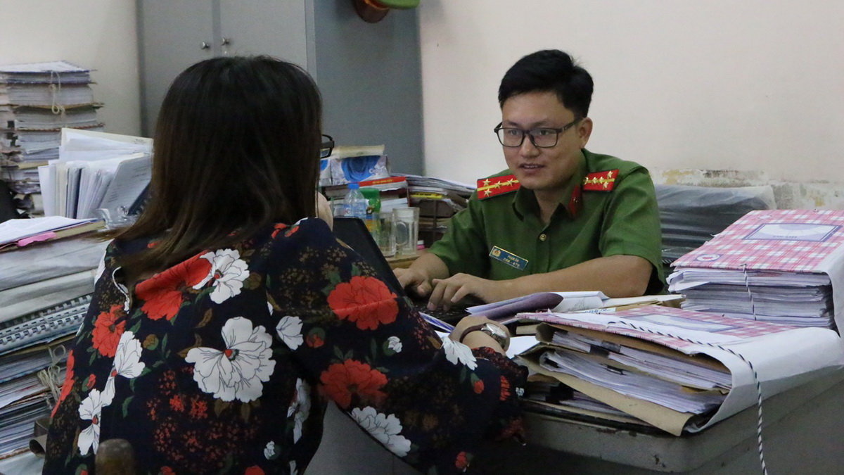 Đại úy Phạm Ân đang ghi lời khai của một nạn nhân bị lừa qua mạng bằng chiêu thức tặng quà, tiền - Ảnh: GIA MINH