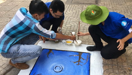 Các bạn sinh viên ĐH Sài Gòn và đoàn viên thanh niên Q.5 cùng thực hiện những “bức tranh nắp cống” tại đường Tản Đà (Q.5, TP.HCM) - Ảnh: Q.NG.