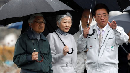 Nhật hoàng Akihito (trái) và Hoàng hậu Michiko đội mưa đi nghe thị trưởng thành phố Soma thuộc tỉnh Fukushima giải thích về tổn hại của trận động đất - sóng thần vào tháng 5-2011, tức hai tháng sau khi thiên tai xảy ra - Ảnh: Reuters