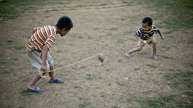 Hòa Bình: Hai chú bé ở Thung Nai, huyện Cao Phong (Hòa Bình) với sợi dây thừng nhặt được và đã lấy gỗ tự đẽo thành con quay đang say sưa chơi trước khu đất trống - Ảnh: Dương Bình