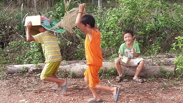 Ba trẻ em nghèo ở xã Triệu Ái, huyện Triệu Phong (Quảng Trị) lấy chiếc thùng đựng bia cộng với một mảnh vải màn cũ chơi trò múa lân mùa Trung thu năm nay - Ảnh: L.Đ.Dục