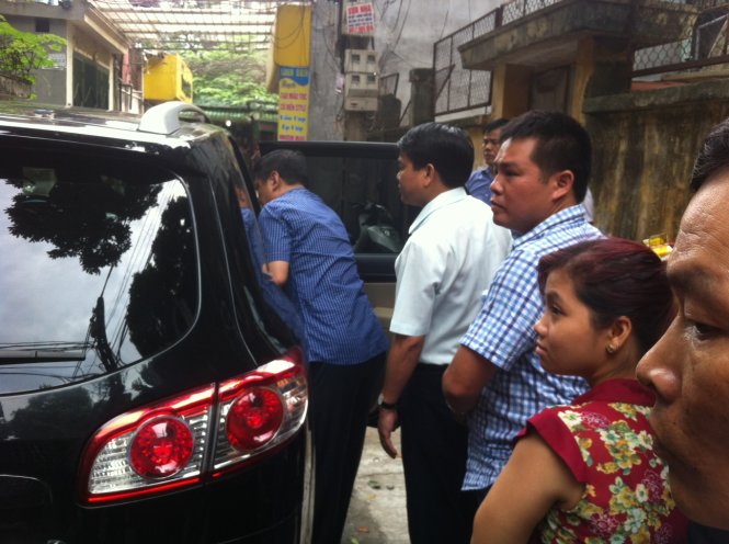 Giám đốc CAHN áo trắng trực tiếp đưa đối tượng ra xe ô tô về trụ sở - Ảnh: Minh Quang