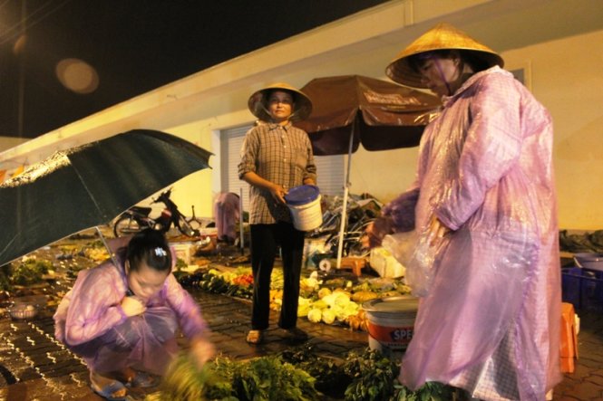 Chị Quế (bên phải) đội mưa bán rau sau khi bị “hôi tiền” - Ảnh: Cảnh Phúc