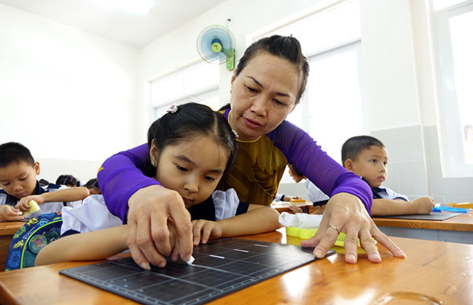 Cô cùng trò tập viết những nét chữ đầu tiên. Trong ảnh: một tiết học của học sinh lớp 1 Trường tiểu học Nguyễn Bỉnh Khiêm, Q.1, TP.HCM - Ảnh: Như Hùng