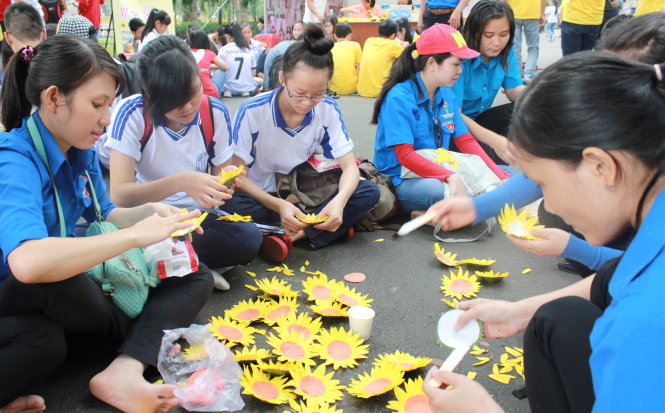Các bạn trẻ tham gia làm hoa hướng dương gây quỹ ủng hộ chương trình “Ước mơ của Thúy” của báo Tuổi Trẻ tại ngày hội - Ảnh: Q.L.