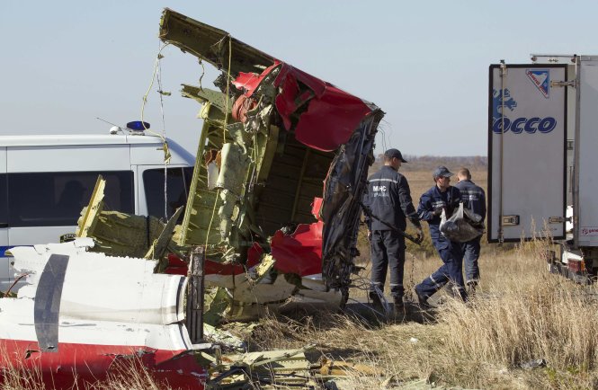 Một thành viên của Trung tâm tình trạng khẩn cấp Nga đang thu nhặt các hiện vật còn lại trên hiện trường vụ MH17 bị bắn rơi - Ảnh: Reuters