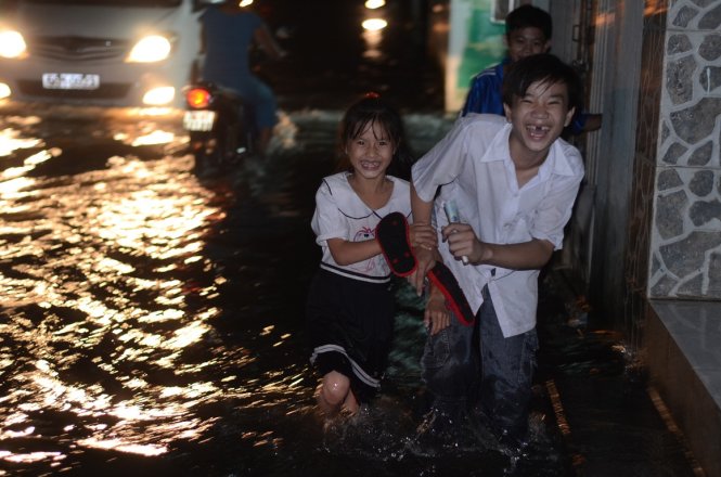 Em Nguyễn Ngọc Quỳnh Trang cùng anh trai của mình lội nước về nhà sau buổi học - Ảnh: T.Tùng