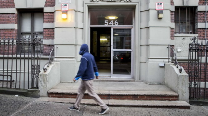 Một người đàn ông đi ngang tòa nhà nơi bác sĩ Craig Spencer sinh sống ở Manhattan, New York - Ảnh: Reuters