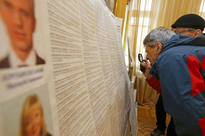 Cử tri xem thông tin về các ứng cử viên tại điểm bầu cử ở Kiev sáng 26-10 - Ảnh: Reuters