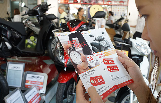 Người dân nghiên cứu tờ rơi hướng dẫn cho vay tín chấp để mua xe máy tại một cửa hàng trên đường Khánh Hội,  Q.4, TP.HCM - Ảnh: Thuận thắng