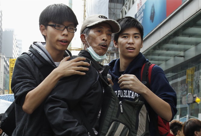 Joshua Wong (trái) và Lester Shum (phải) giữ một người biểu tình khi quan sát cử động của cảnh sát ở khu Mongkok hôm qua - Ảnh: Reuters