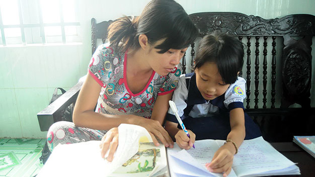 Chị Đinh Thị Thanh giúp con gái Nguyễn Thị Ngọc Lan học bài - Ảnh: A Lộc