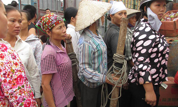 Những phụ nữ ngoại tỉnh xếp hàng chờ việc tại một điểm lao động ở Hà Nội - Ảnh: T.H.