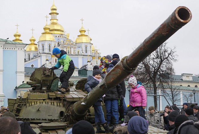 Người dân Ukraine trên một chiếc xe tăng thu được từ quân ly khai và được trưng bày tại thủ đô Kiev - Ảnh: Reuters