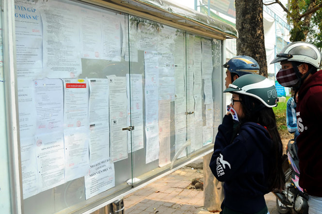Người tìm việc, công nhân đang xem thông báo tuyển dụng đặt trong khuôn viên Khu công nghiệp Amata (P.Long Bình, TP Biên Hòa, Đồng Nai) ngày 9-3 - Ảnh: Hà Mi