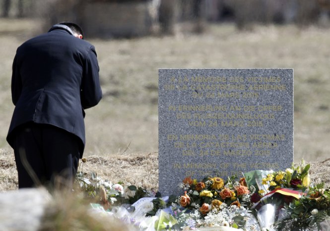 Một người đàn ông đang cúi mình trước tấm bia tưởng niệm các nạn nhân trong vụ tai nạn máy bay ở làng Le Vernet - Ảnh: Reuters