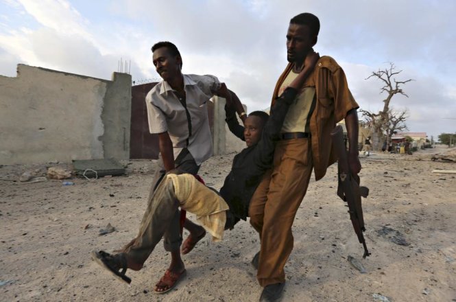 Cư dân sơ tán một cậu bé bị thương sau khi nhóm Hồi giáo al Shabaab tấn công khách sạn Maka Al-Mukarama ở Mogadishu, Somalia ngày 27/3/2015 - Ảnh: Feisal Omar