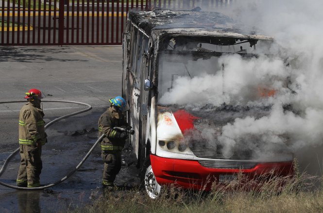 Lính cứu hỏa Mexico đang dập lửa cho một chiếc xe buýt thiệt hại nghiêm trọng tại bang Jalisco, nơi thường xuyên xảy ra các vụ đụng độ giữa các băng nhóm tội phạm - Ảnh: AFP​
