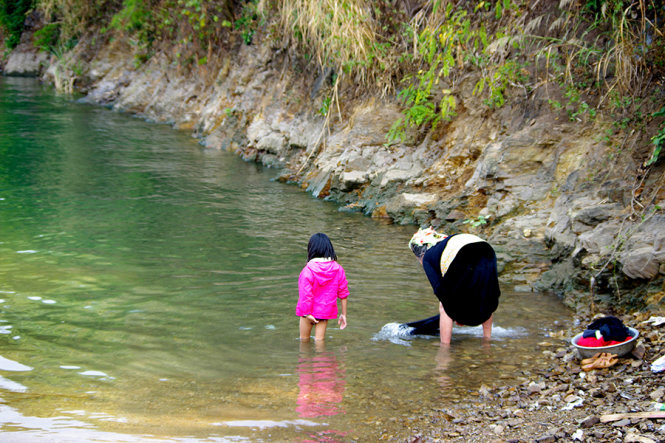 Hai bà cháu giặt quần áo bên sông - Ảnh: Ngọc Phạm