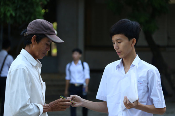 Giao điện thoại cho bố trước khi vào phòng thi tại điểm thi Trường ĐH Sư phạm Huế - Ảnh: Thái Lộc