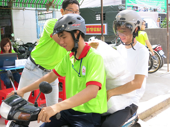 Bạn Đinh Trần Thế Anh (áo trắng ngồi) phụ giúp đem cơm cho thí sinh - Ảnh: T.Trang