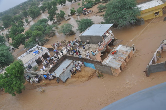 Người dân Ấn Độ đứng trên mái nhà ở quận Surendranagar, bang Gujarat, cầu cứu xin giúp đỡ - Ảnh: Reuters