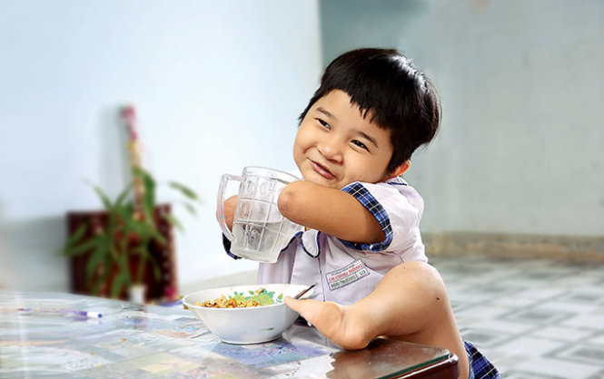 Bé Hoài Thương (7 tuổi) bị dị tật cả hai tay lẫn hai chân tự đút cơm ăn, uống nước và cười tươi như hoa - Ảnh: Vũ Thủy