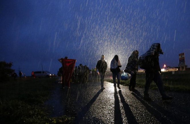 Những bóng người di cư đi lại dưới cơn mưa nặng hạt ở biên giới Áo – Hungary - Ảnh: AP