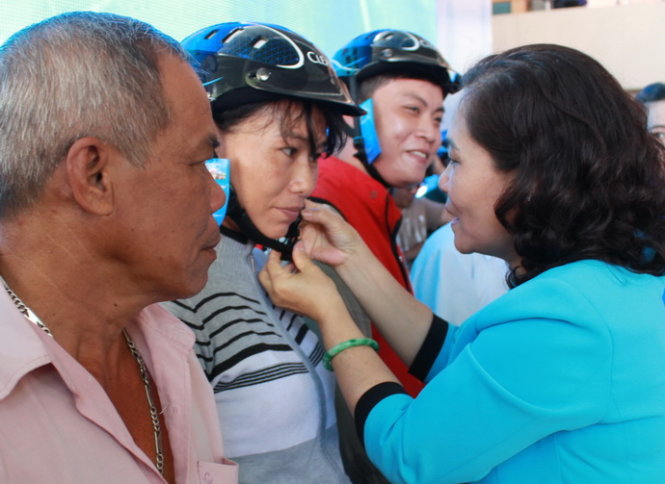 1: Phó trưởng ban thường trực Ban Dân vận Thành ủy TP.HCM Nguyễn Thị Lệ đeo mũ bảo hiểm tặng cho một nữ tài xế xe ôm Ảnh: Q.L.