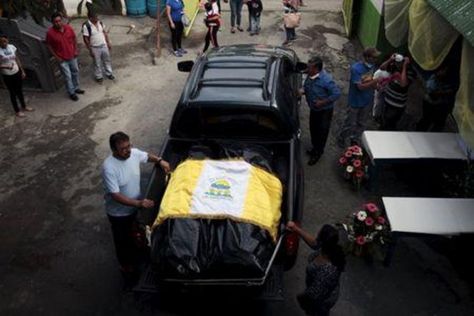 Người dân che phủ thi thể các nạn nhân thiệt mạng bằng một lá cờ ở Santa Catarina Pinula - Ảnh: Reuters