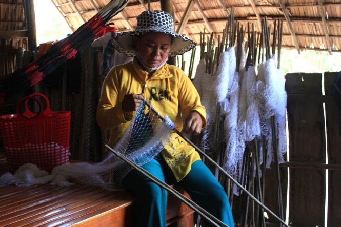 Chị Dương Thị Tuốt và đống lưới mới chưa sử dụng vì lũ chưa về, dù chị đã bỏ tiền thuê đồng lũ để bắt cá - Ảnh: Sơn Lâm