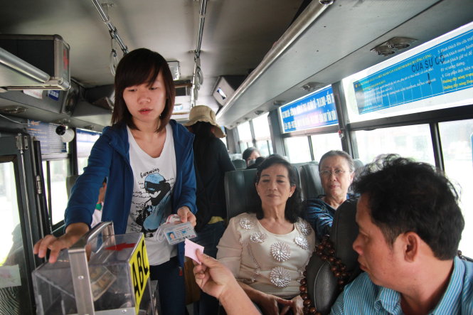 Hành khách bỏ tiền vào thùng bán vé tự động trên tuyến xe buýt số 152 - Ảnh: Hữu Khoa