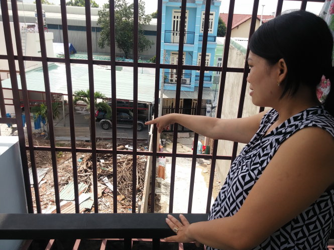Chị Vân đứng tại tầng 2 của căn nhà bị nứt tường nhìn xuống hiện trường vụ nổ hóa chất cách đây một năm             Ảnh: ĐỨC THANH