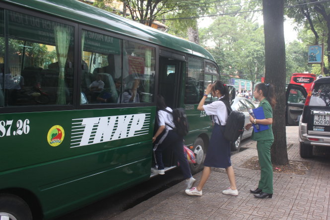 Nữ nhân viên Lực lượng Thanh niên xung phong TP hướng dẫn các em học sinh lên xe đưa rước - Ảnh: Đức Phú