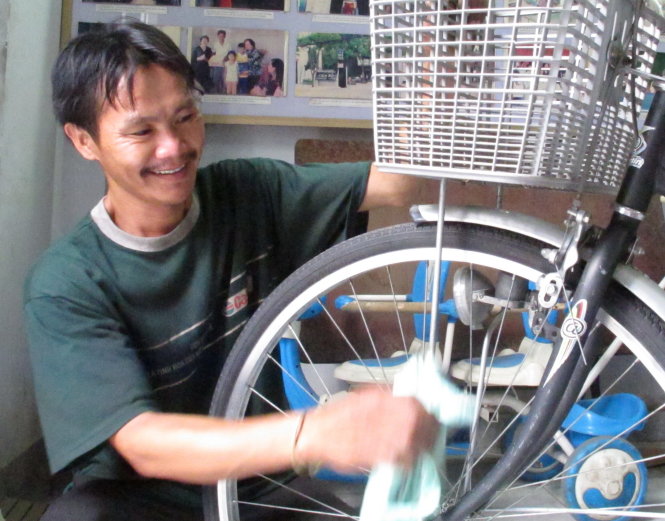 Anh Lê Văn Thái lau chùi chiếc xe đạp chuẩn bị làm quà tặng học trò nghèo - Ảnh: K.Anh