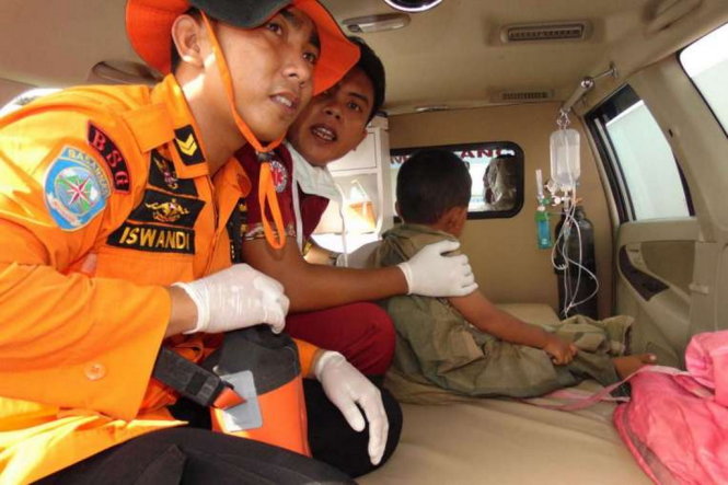 Lực lượng cứu hộ đang đưa một bé trai được cứu sống vào bờ - Ảnh: AFP