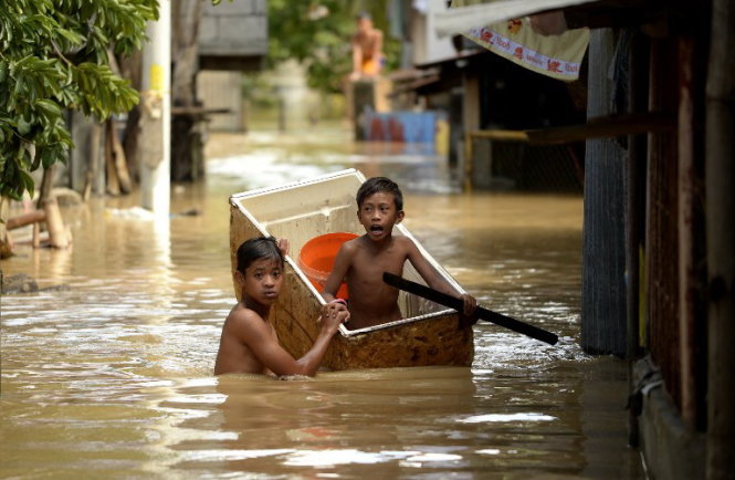 Trẻ em di chuyển trên đường ngập ở Candaba, phía bắc Manila - Ảnh: AFP