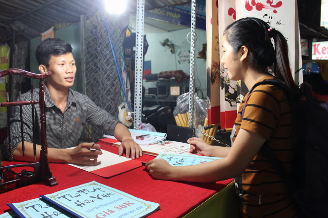 Bạn Nguyễn Hữu Việt (sinh viên năm 3 Trường ĐH Thể dục thể thao TP.HCM) viết thư pháp tại chợ đêm làng đại học Thủ Đức - Ảnh: M.Nương