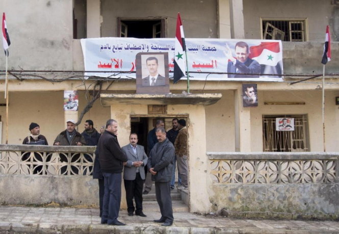 Những người ủng hộ tổng thống Syria Bashar Al Assad trước một tòa nhà ở Salma ngày 22-1 - Ảnh: AP