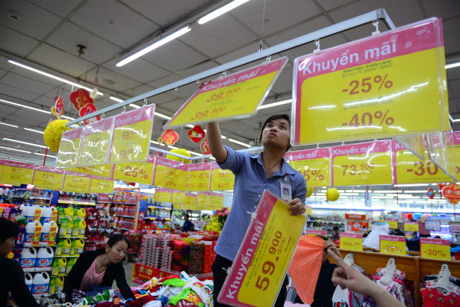 Nhân viên Co.op Mart Đinh Tiên Hoàng (TP.HCM) thay bảng giá hàng khuyến mãi tại siêu thị chiều 28-1 - Ảnh: Thanh Tùng