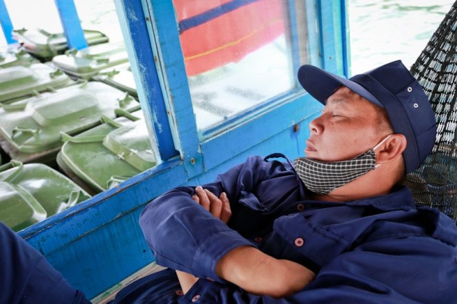 Anh Phạm Lợi tranh thủ chợp mắt trong lúc thuyền gom rác đi đến từng điểm đảo - Ảnh: Tiến Thành