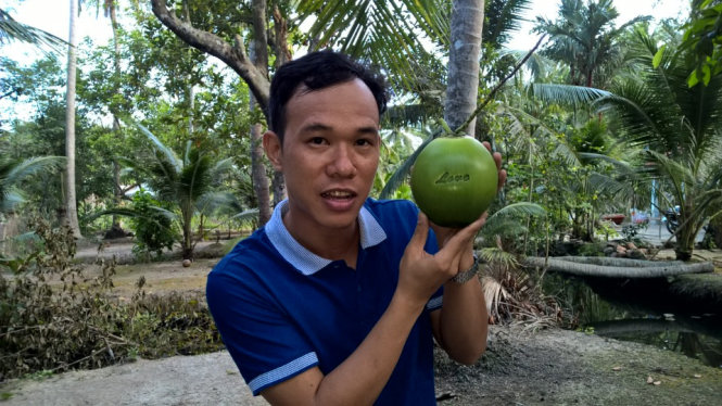 Anh Huỳnh Thanh Tâm với những trái dừa in chữ độc đáo do chính anh làm ra