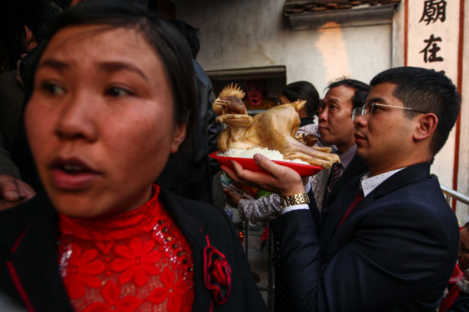 Một người đàn ông cung tiến gà để làm lễ - Ảnh: Nguyễn Khánh
