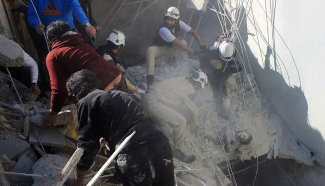 Một nạn nhân bị mắc kẹt trong đống đổ nát sau một cuộc không kích được cho là của Nga tại Syria - Ảnh: AFP