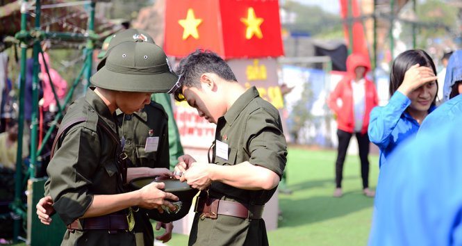 Một chiến sĩ tham gia nghĩa vụ công an sửa nón giúp đồng đội - Ảnh: Thanh Tùng