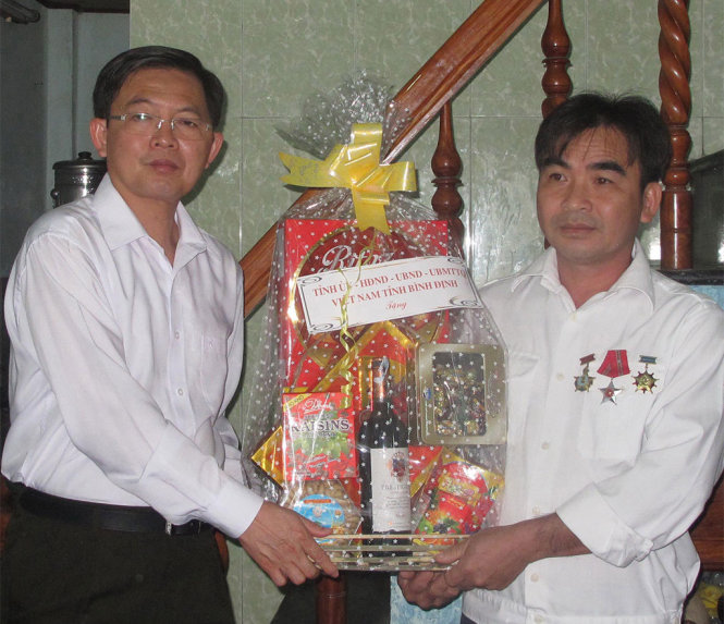 Chủ tịch UBND tỉnh Bình Định Hồ Quốc Dũng (bên trái) tặng quà cho cựu chiến binh Lê Minh Thoa - Ảnh: N.Trần