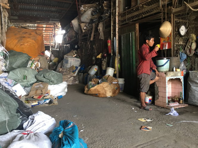 Nhân viên của một vựa phế liệu ở Q.Bình Tân, TP.HCM dù đang đóng bao phế liệu nhưng vẫn thản nhiên hút thuốc - Ảnh: Đức Thanh