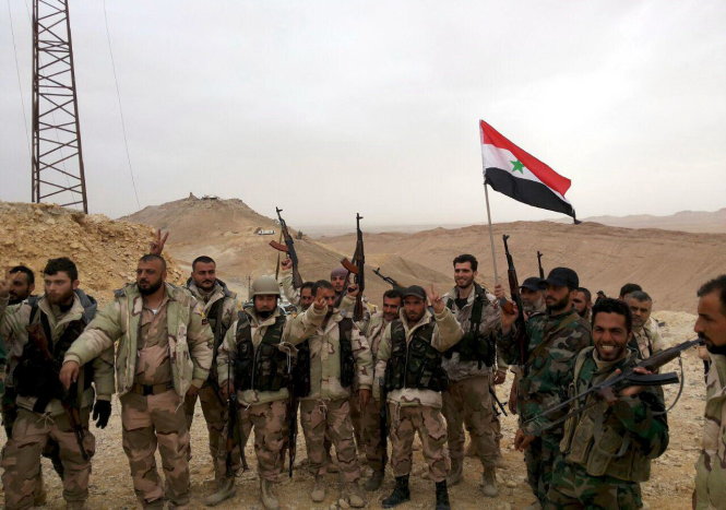 Lực lượng dân quân trung thành với chính quyền Damascus giương cờ Syria mừng chiến thắng tại thành phố Palmyra - Ảnh: Reuters