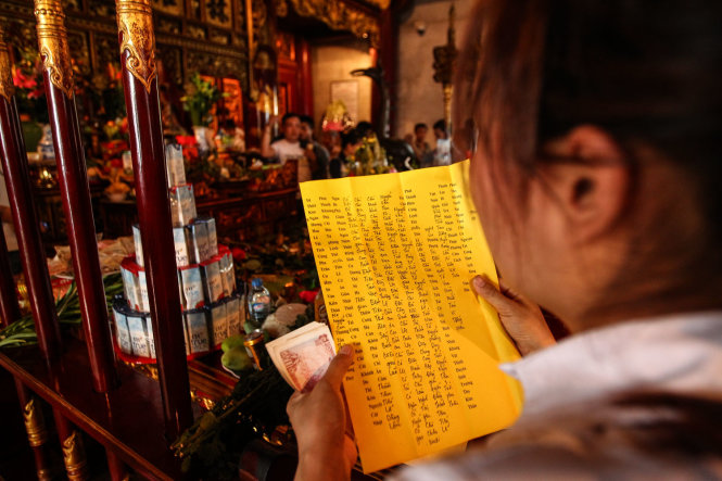 Một cô gái đang cầm lá sớ để đọc trong khi làm lễ tại đền Thượng - Ảnh: Nguyễn Khánh