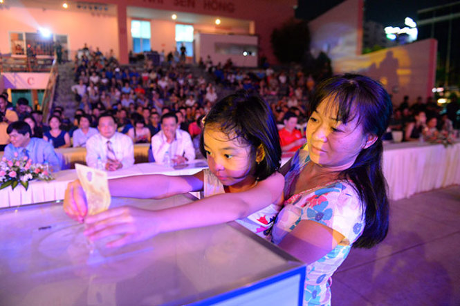 Bé Nguyễn Phạm Thúy Hạnh (7 tuổi) cùng mẹ tham gia ủng hộ cho người dân vùng hạn, mặn - Ảnh: Hữu Khoa